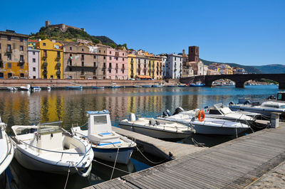 Boats moored at harbor against buildings in city