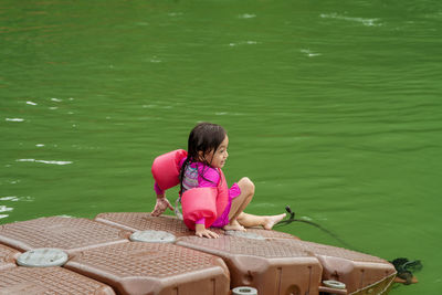 Rear view of woman sitting on pink water