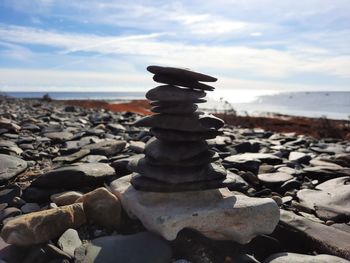 Stack of stones on beach against sky