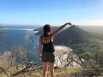 Woman pointing at beach against mountains