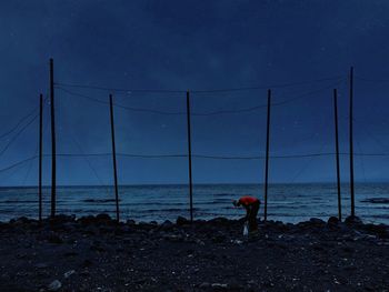 Man fishing in sea against sky at night