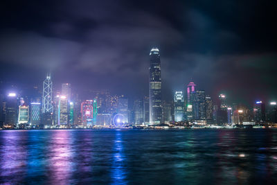 Illuminated modern buildings in city against sky at night