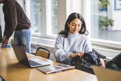 Young woman with laptop at desk in classroom