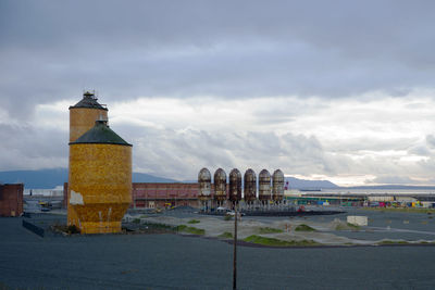 Lighthouse by sea against buildings in city