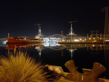 Illuminated pier by sea against sky at night