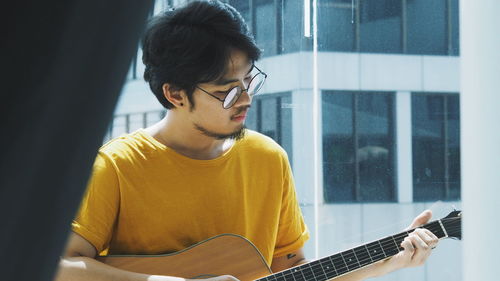 Young man playing guitar at home