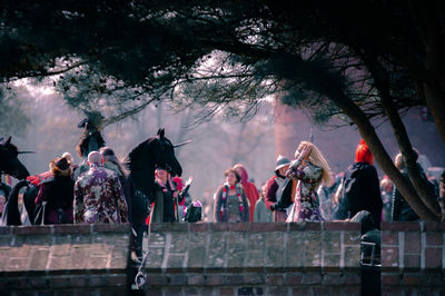 People standing by railing against trees