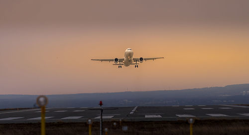 Low angle view of airplane flying against sky during sunset