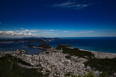 High angle view of townscape by sea against blue sky