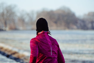 Rear view of woman walking on snow covered field