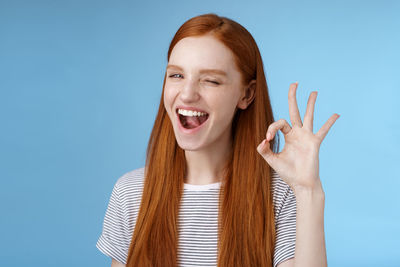 Portrait of young woman against blue background