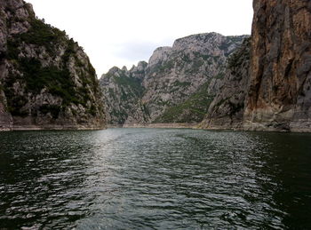 Scenic view of sea by mountains against sky