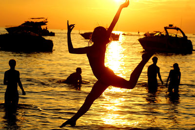 Silhouette people at beach against sky during sunset