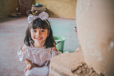 High angle portrait of cute smiling girl crouching in workshop