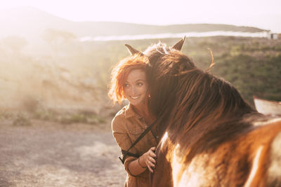 Woman standing by horse on field