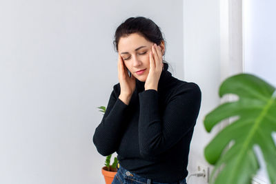 The woman has a headache, she sits down on a chair, closes her eyes and wraps her head in her hands