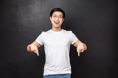 Portrait of smiling man standing against black background