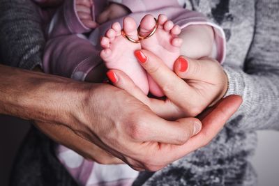 Midsection of parents carrying baby