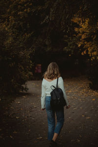 Rear view of woman walking on footpath in forest