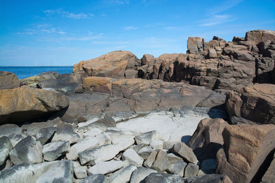 Rocks by sea against blue sky