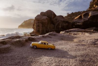 Car on rock formation at beach against sky