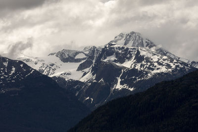 Cloudy gray sky over snowy mountain peak