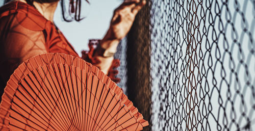 Close-up of man looking through chainlink fence