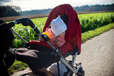 Cute toddler girl in baby carriage on roadside