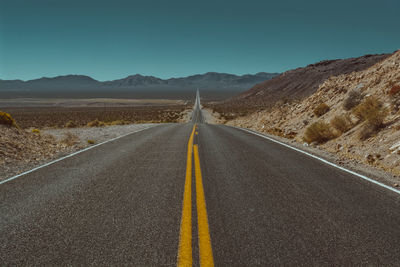 Road leading towards mountains against sky