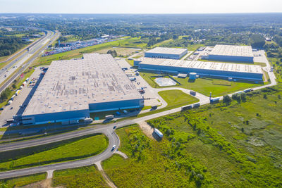 Aerial top view of industrial storage building area with solar panels on the roof and many trucks 