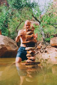 Young woman smiling while sitting by tree