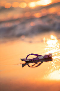 Close-up of sunglasses on beach against sky during sunset
