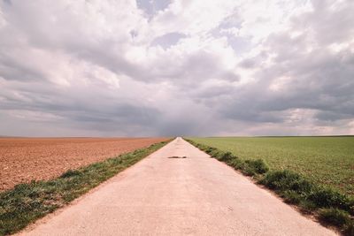 Road amidst field against sky