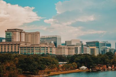 Buildings by river against sky in city