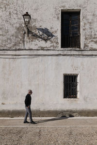 Portrait of adult man in suit walking against white wall with windows