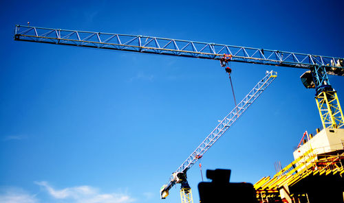 Low angle view of crane against blue sky