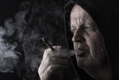 Close-up of man smoking against black background