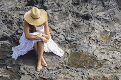 Full length of woman sitting on rock