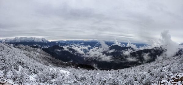 Panoramic view of mountains against cloudy sky during winter