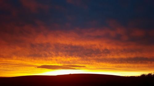 Scenic view of dramatic sky over silhouette landscape