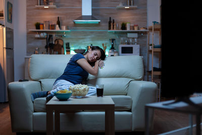 Young woman sitting on sofa at home