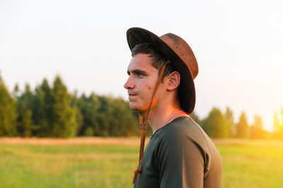 Portrait of young woman wearing hat standing on field