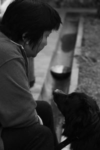 Dog looking at depressed woman sitting outdoors