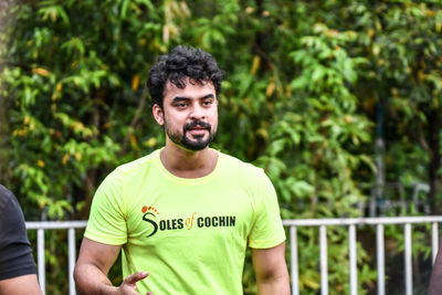 Portrait of young man standing against trees