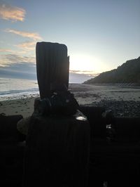 Close-up of camera on beach against sky during sunset