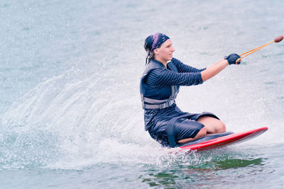 Side view of young woman kiteboarding on sea