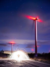 Wind turbines on field against sky at night