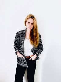 Portrait of young woman standing against white background