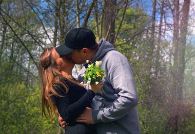Couple kissing on tree in forest