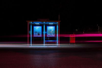 Light trails on road against bus stop at night